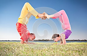 Yoga couple, man and woman doing Vrschikasana scorpion pose