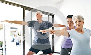 Yoga really does benefit anyone and everyone. an instructor guiding a senior couple in a yoga class.