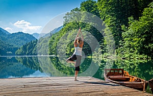 Yoga exercises at mountain forest lake.