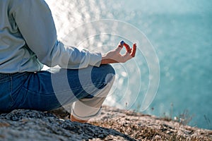 yoga, gesture and healthy lifestyle concept - hand of meditating yogi woman showing gyan mudra over sea sunset