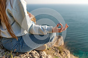 yoga, gesture and healthy lifestyle concept - hand of meditating yogi woman showing gyan mudra over sea sunset