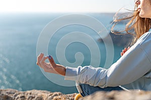 yoga, gesture and healthy lifestyle concept - hand of meditating yogi woman showing gyan mudra over sea sunset