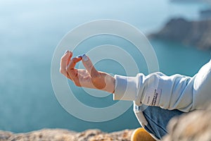 yoga, gesture and healthy lifestyle concept - hand of meditating yogi woman showing gyan mudra over sea sunset