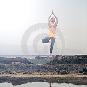 Yoga girl meditating and relaxing in yoga pose, ocean view