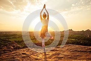 Yoga in Hampi temple copyspase at sunset.travel vacation copy spase lady with stylish jumpsuit