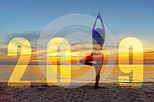 Yoga Happy new year card 2019. Silhouette lifestyle woman practicing yoga standing as part of Number 2019 near the beach at sunset