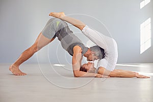 Couple yoga pose on the floor in a studio class.