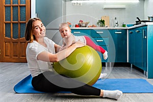 Yoga at home. A young mother leaning on a fit ball and posing with your baby. The concept of fitness with children at