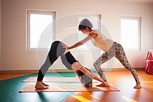 Yoga instructor assisting student in exercis