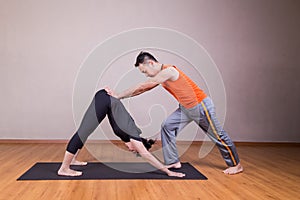 Yoga instructor guiding student perform downward facing dog pose