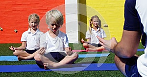 Yoga instructor instructing children in performing yoga