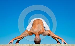 Yoga instructor with muscular body stretching. Sport and health care. Coach demonstrate yoga asana outdoors. Flexible