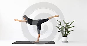 Yoga instructor performing Virabhadrasana exercise, warrior number three pose, working out in short leggings and a T-shirt