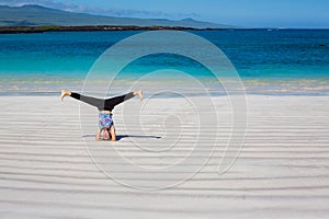 Yoga Instructor performs hand stand on Cerro Brujo Beach in Galapagos