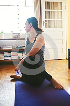 Yoga is the key to fitness. an attractive young woman sitting and holding a spinal half twist while doing yoga in her