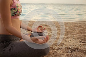 Yoga lifestyle. Close up. Young woman meditating, practicing yoga and pranayama with gyan mudra at the beach, Bali