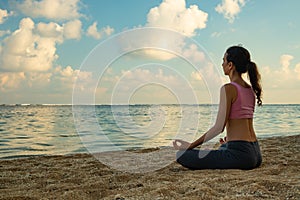 Yoga lifestyle. Young woman meditating, practicing yoga and pranayama with gyan mudra at the beach, Bali