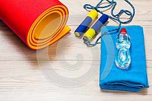 Yoga mat and different tools for fitness on floor in room.