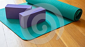 Yoga mat and exercise bricks on wooden floor, pilates yoga class concept