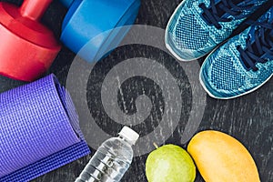Yoga mat, sport shoes, dumbbells and bottle of water on blue background. Concept healthy lifestyle, sport and diet. Sport equipmen