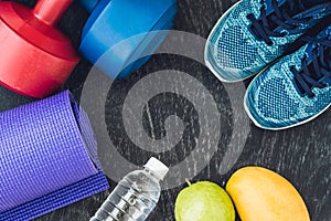 Yoga mat, sport shoes, dumbbells and bottle of water on blue background. Concept healthy lifestyle, sport and diet. Sport equipmen