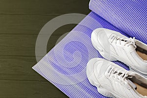 Yoga mat and sports shoes on a black background. Healthy lifestyle, yoga, the concept of s.ports