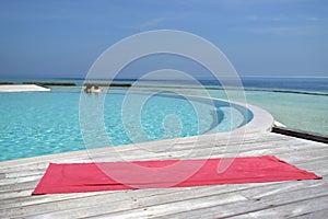 Yoga mat by the swimming pool next to the sea