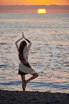 Yoga and meditation on calm beach at sunrise