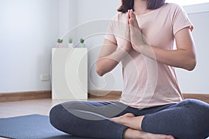 Yoga and meditation lifestyles. close up view of young beautiful woman practicing yoga namaste pose in the living room at home