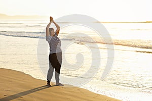 Yoga and meditation of mature woman practicing breath exercises on the sea beach on sunrise in the morning. Body mind