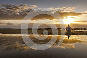 Yoga meditation silhouette lotus sunrise beach, water reflection of man in yoga pose, mindfulness wellbeing concept photo