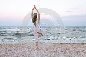 Yoga meditation woman meditating at beach sunset relaxing in yoga posture, tree pose, vrksasana. Relaxed serene woman enjoying eve