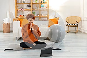 Yoga mindfulness meditation. Young healthy african girl practicing yoga at home. Woman sitting in lotus pose on yoga mat