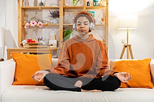 Yoga mindfulness meditation. Young healthy african girl practicing yoga at home. Woman sitting in lotus pose on yoga mat