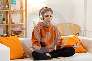 Yoga mindfulness meditation. Young healthy african girl practicing yoga at home. Woman sitting in lotus pose on yoga mat