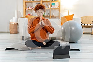 Yoga mindfulness meditation. Young healthy african girl practicing yoga at home. Woman sitting in lotus pose on yoga mat