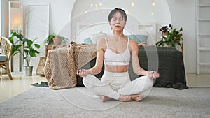 Yoga mindfulness meditation. Young healthy woman practicing yoga in living room at home. Woman sitting in lotus pose