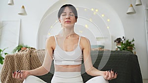 Yoga mindfulness meditation. Young healthy woman practicing yoga in living room at home. Woman sitting in lotus pose