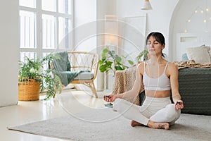 Yoga mindfulness meditation. Young healthy woman practicing yoga in living room at home. Woman sitting in lotus pose