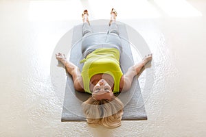 Yoga nidra practice. Caucasian adult woman lying on the floor in shavasana in the loft studio indoor, top front view