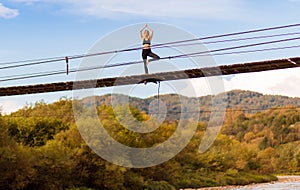 Calm woman doing yoga balance exercises. Yoga meditation on bridge over river with mountains background. Concept of