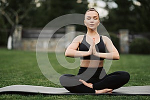 Yoga outdoor. Happy woman doing yoga exercises, meditate in the park. Yoga meditation in nature. Concept of healthy lifestyle and