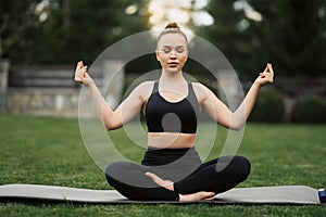 Yoga outdoor. Happy woman doing yoga exercises, meditate in the park. Yoga meditation in nature. Concept of healthy lifestyle and
