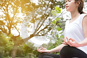Yoga outdoors in public park. Asian woman sits in lotus position