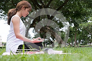 Yoga outdoors in public park. Asian woman sits in lotus position