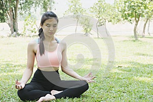 Yoga outdoors in summer park. young woman sits in lotus position