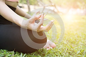 Yoga outdoors in summer park. young woman sits in lotus position