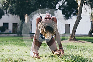 Yoga - outdoors young beautiful slender woman yoga instructor doing camel pose Ustrasana asana exercise outdoors.