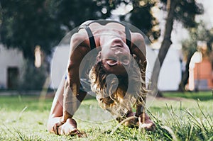 Yoga - outdoors young beautiful slender woman yoga instructor doing camel pose Ustrasana asana exercise outdoors.