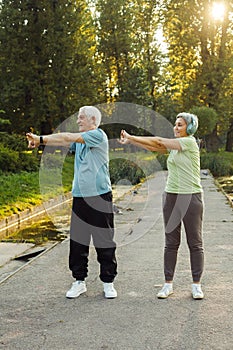 Yoga at park. Senior family couple exercising outdoors.